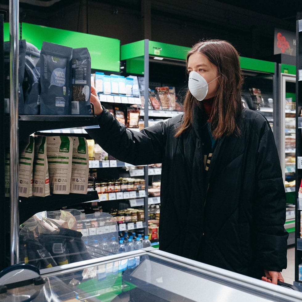 A woman wearing a surgical mask shopping groceries