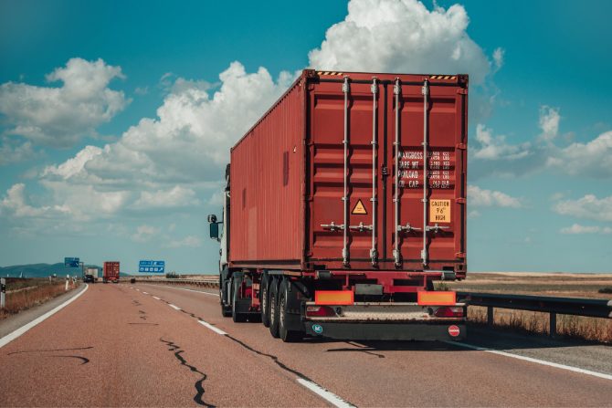 a red truck on the highway to illustrate a blog article about sustainable transportation regulations.