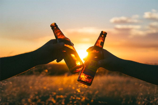 two hands holding beers cheering