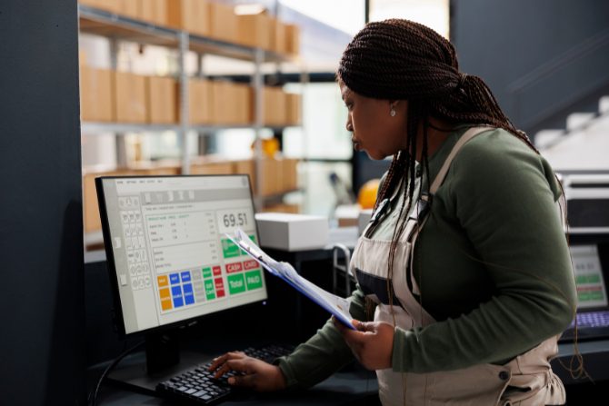Warehouse worker monitoring inventory levels on a computer, symbolizing the shift from just-in-time to just-in-case inventory management for supply chain resilience.